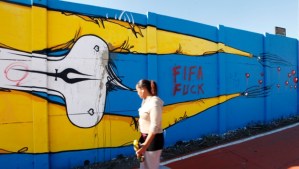 A woman walks past a graffiti referring to the 2014 World Cup in Sao Paulo