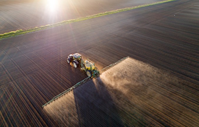 Tractor spraying young crops in field