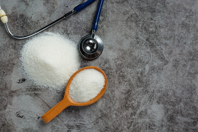World diabetes day; sugar in wooden bowl and stethoscope on dark background
