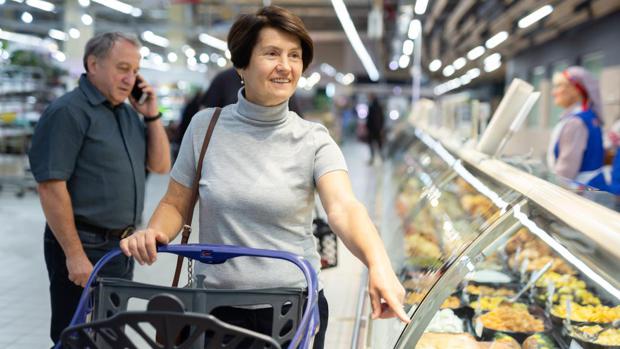 Elderly couple of spouses buy ready-made meals for picnic with friends in culinary department. Model